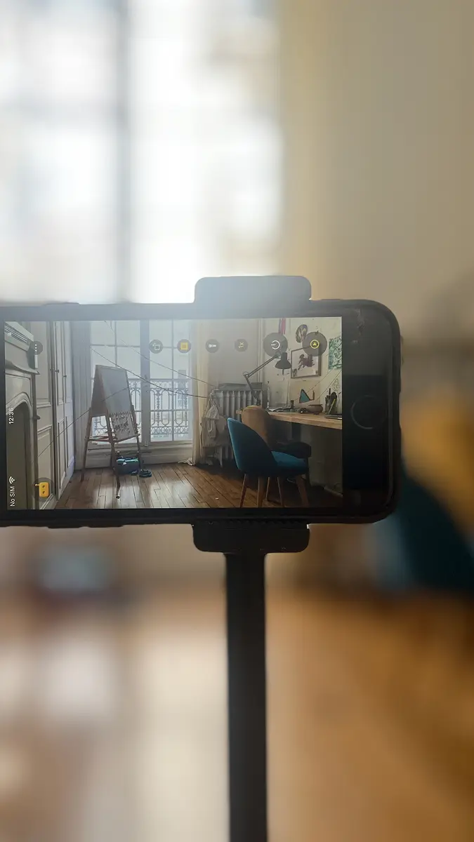 Un ancien iPhone sous RECAM utilisé comme caméra maison, posé sur le rebord d’une fenêtre et branché sur secteur